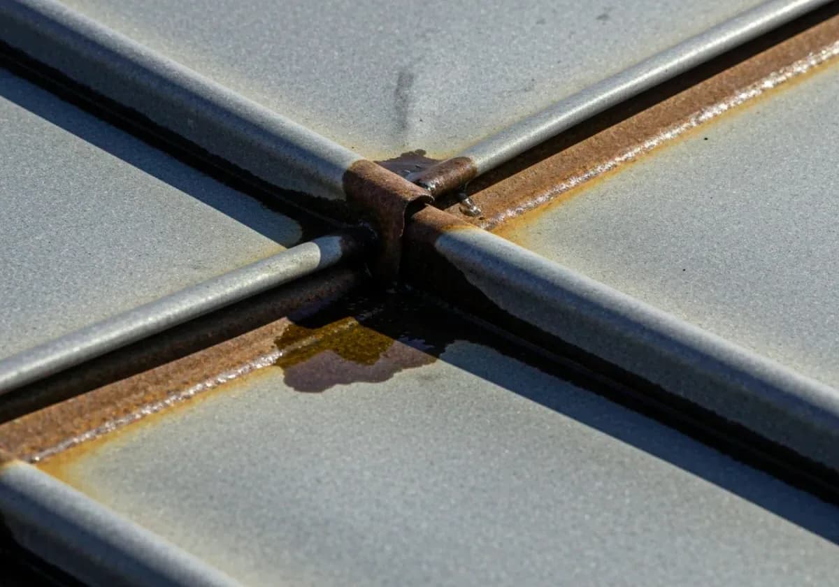 Before — chimney flashing repair: Rusted, leaking flashing stripped and re-layered where chimney meets roofline.